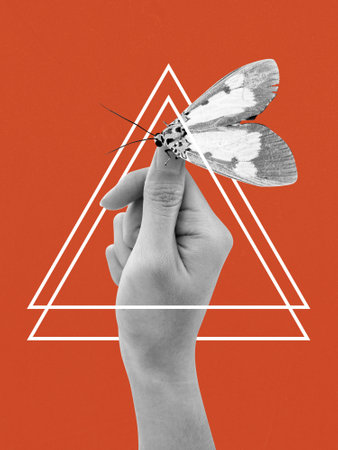 Human hand holding a moth illustration isolated on orange background. Surreal and dream conceptの写真素材