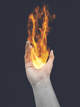 Hand holding burning flame and fire isolated on dark background. Symbol of hope.の写真素材