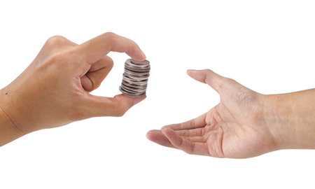 Donating money concept. Giving spare changes. Hand holdings stacks of coins and other hands prepare to receive it. Helping others in need.の写真素材