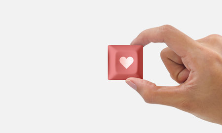 Hand holding pink button with heart icon isolated on white background. Love and intimacy concept for valentine's dayの写真素材