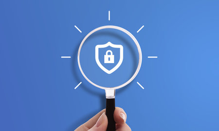 Hand holding magnifying glass with locked shield icon, symbol of cybersecurity, secure connection, and protected privacy.の写真素材