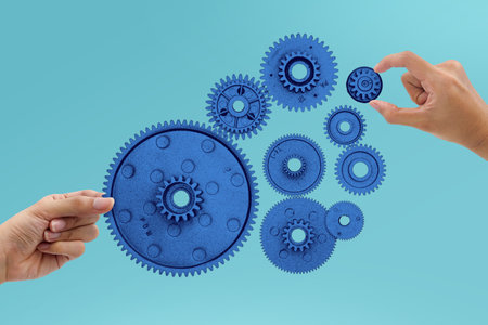 Two hands assembling blue gears on a gradient blue background. Collaboration, teamwork, and mechanical innovation collage concept.の写真素材