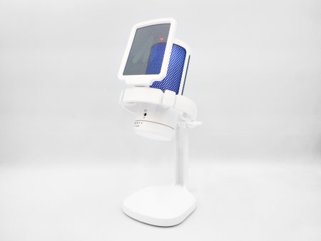 White microphone with pop filter on a desktop stand isolated in white background. Studio photoshoot for electronic product display, side viewの写真素材
