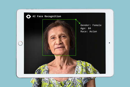 AI facial recognition system on tablet screen analyzing old Asian lady face, identifying gender, age, and race. Futuristic labelling technology concept.の写真素材