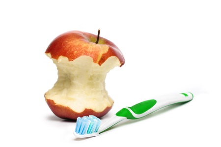 A toothbrush and an apple in the background. Focus is pointed at the bristle brushの写真素材