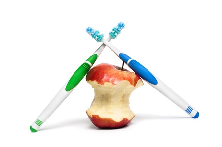 Two  toothbrushes and an apple on a white backgroundの写真素材