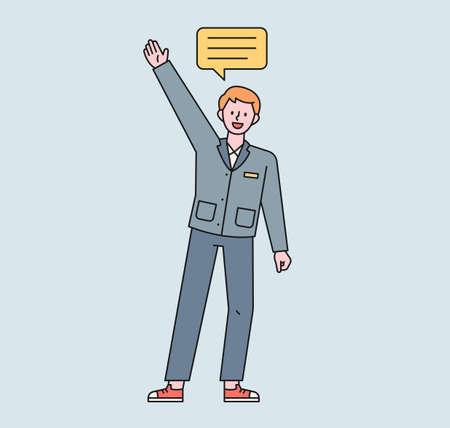 A male student in a school uniform raises his hand and speaks. A speech bubble floats above the boy's head. flat design style minimal vector illustration.のイラスト素材
