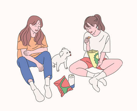 Two friends are sitting on the floor, eating snacks, watching the puppy and having fun. hand drawn style vector design illustrations.のイラスト素材