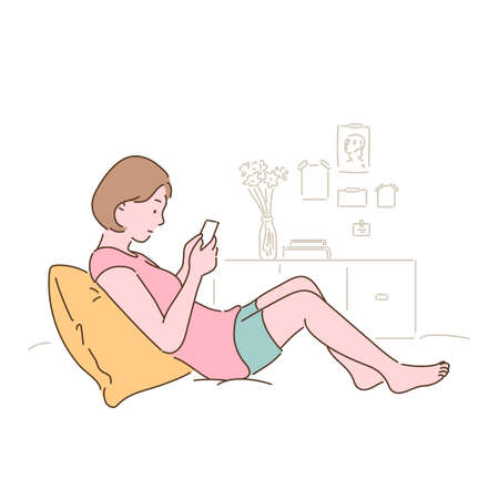 A woman is sitting on her bed and looking at her phone. hand drawn style vector design illustrations.のイラスト素材