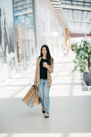 Attractive girl in with the shopping bags and warm drink in her handの写真素材