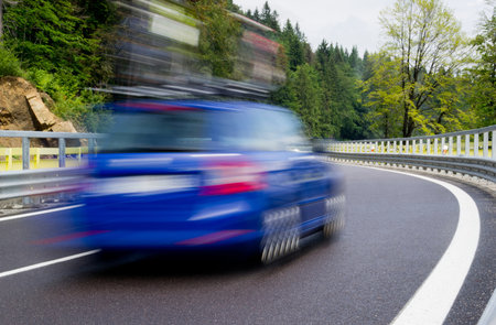 Fast blurred blue car on a twisty mountain roadの写真素材