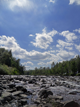 Mountain stream with small waterfalls and blue sky
