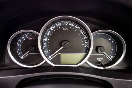 A detail of a dashboard of a modern car with odometer and other instruments showing values as rpm...
