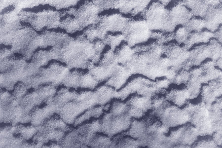 Abstract background texture of white snow and strong shadows with a blue tint