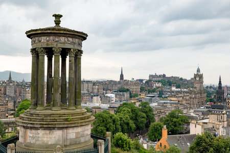 EDINBURGH, SCOTLAND - JULY 30, 2019: The memorial of Dugald Stewart on the Calton hill with a view at Edinburgh cityscape with the Balmoral, the castle and The Hubのeditorial素材