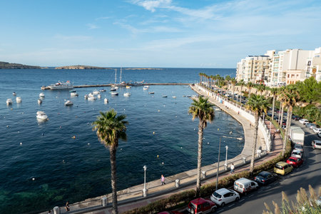 BUGIBBA, ST PAULS BAY, MALTA - OCTOBER 27, 2019: The cityscape of Bugibba city in Malta with a view at the sea, port, palms and the Dawret il-Gzejjer streetのeditorial素材