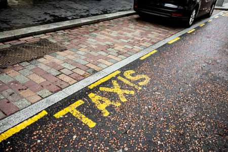 Parking lane for taxi cars and cabs in Brittish and Scottish cities with a yellow text on a black roadの写真素材