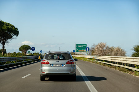 CINISI, SICILY - FEBRUARY 9, 2020: A grey car on a Sicilian highway travelling through this beautiful Southern European island. The highway is equipped with crash barriers and navigation boardsのeditorial素材