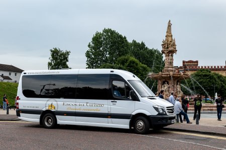GLASGOW, SCOTLAND - JULY 31, 2019: Mercedes-Benz Sprinter touristic shuttle bus of the Escocia Turismo company in the Glasgow Green park in front of the Doulton Fountainのeditorial素材