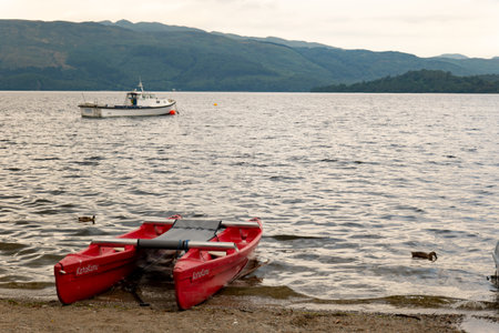 LUSS, SCOTLAND - AUGUST 1, 2019: A red KataKanu boat at Loch Lomond lake in Scotland to be hired by touristsのeditorial素材