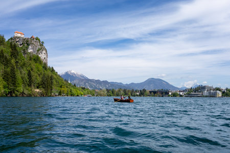 BLED, SLOVENIA - APRIL 18, 2014: Tourists rowing on a boat on Bled Lake with the Bled Castle in Slovenia, Europe in the backgroundのeditorial素材