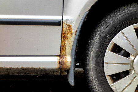 Detail of a rusty underside and mudguard of a silver car. Neglected care of the vehicle and the result of salt on winter roadsの写真素材