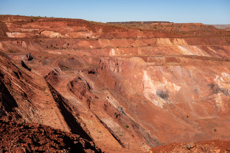 Active deep pit of red iron ore mine in Pilbara region in Western Australia with shadows of various...