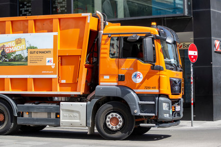 VIENNA, AUSTRIA - JULY 27, 2021: Orange dumpster truck MAN TGS 26.320 in the centre of Vienna removing the garbageのeditorial素材