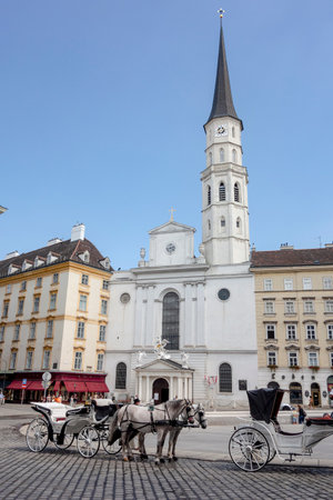 VIENNA, AUSTRIA - JULY 28, 2021: Horse and buggy waiting for passengers standing in front of Michaelerkirche church near Hofburg, Vienna, Austriaのeditorial素材