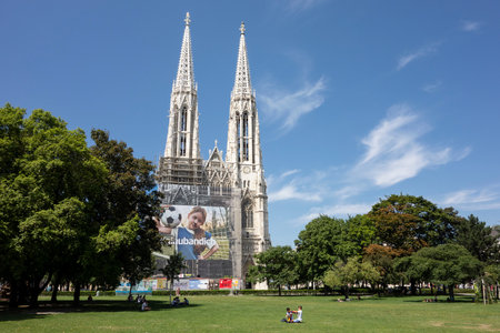 VIENNA, AUSTRIA - JULY 28, 2021: Votivkirche church in centre of Vienna capital city which is under reconstruction with an advertisment on the scaffoldingのeditorial素材