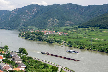 Landscape with ferry ship and heavy freight vessel on a Danube river in Austria near Spitz townの写真素材
