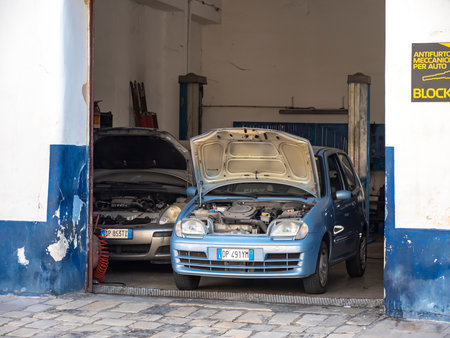 BRINDISI, ITALY - OCTOBER 28, 2021: Blue Fiat Seicento with open hood in a small service garage to be fixedのeditorial素材