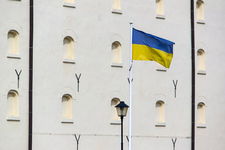 Ukrainian flag waving in wind on Polish building showing the support to the countryの写真素材