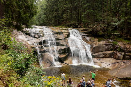 HARRACHOV, CZECH REPUBLIC - AUGUST 22, 2020: Mumlavsky vodopad waterfall in Krkonose (Giant Mountains) in the Mumlava river with tourists visiting the landmarkのeditorial素材