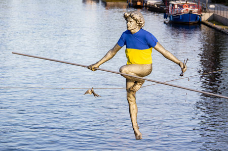 BYDGOSZCZ, POLAND - AUGUST 10, 2022: Przechodzacy Przez Rzeke statue above the Brda river with Ukrainian flag T-shirt in Bydgoszczのeditorial素材