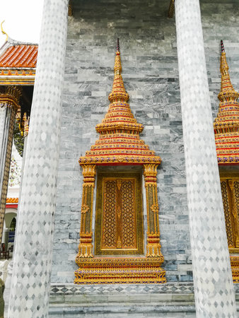 golden window of Thai temple with grey marble wall