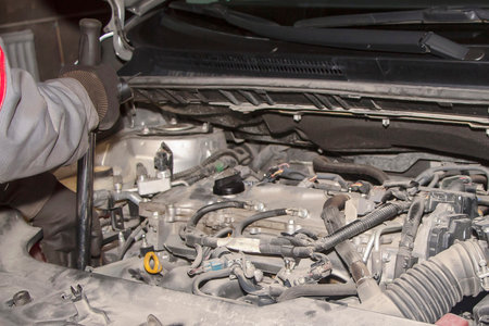 A hand technician checking or fixing the engine of a modern car.の写真素材