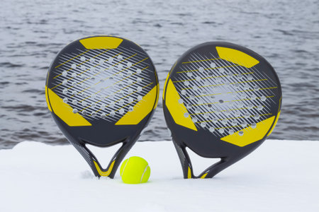 Ball and two beach tennis rackets on the snow covered beach against the background of the sea.の写真素材