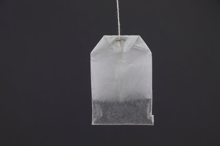 A white tea bag on a dark background.