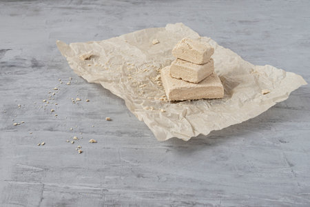 Peanut halva lying on parchment paper on a gray background. Traditional national dessert. Turkish, Arabic, Oriental cuisine.の写真素材