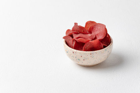 Raw smoked pork meat chips with spices in a ceramic bowl on a white textured background. Appetizer for beer. Close-up, copy space, horizontal orientation.の写真素材