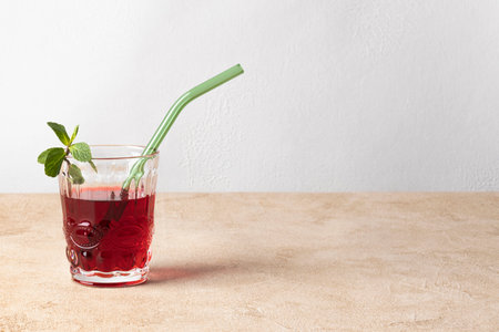 Karkade tea (hibiscus) in a glass with mint leaves and a glass tube for drinks. Horizontal orientation, copy space.の写真素材