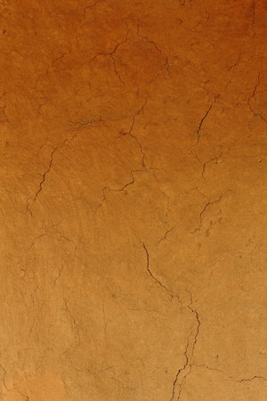 Old cracked wall made of orange clay and straw の写真素材