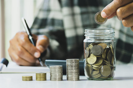 Business man putting the money in glass jar to saving,financial,accounting concept.