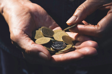 Close up hand holding coins for saving concept on dark background.