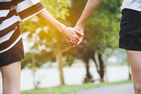 Closeup female holding hand standing and walking on the sidewalk with the lighting on.の写真素材
