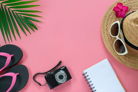 Flat lay, top view with hat,slippers,camera,notebook,sunglasses,flower and green leaf tropical palm for travel,summer and holiday concept on soft pink background.の写真素材
