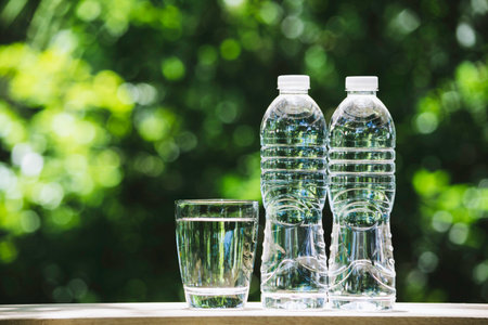 Pure water in plastic bottle and water glass  on wooden in nature background.