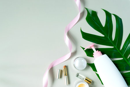 Top view product of beauty care for body or skin with lotion lip and pink ribbon and green leaves background.の写真素材