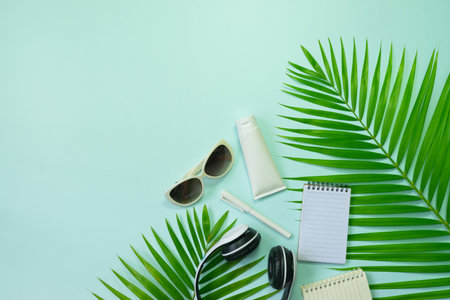 Flat lay, top view with hat,pen,shoes headphone,camera,notebook and green leaf tropical palm for travel,summer and holiday concept on soft blue background.の写真素材